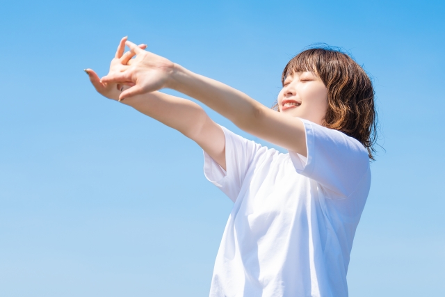 夏の青空と白いTシャツを着た笑顔の女性