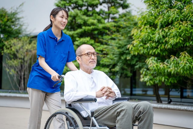 車いすのシニア男性と介護施設スタッフ